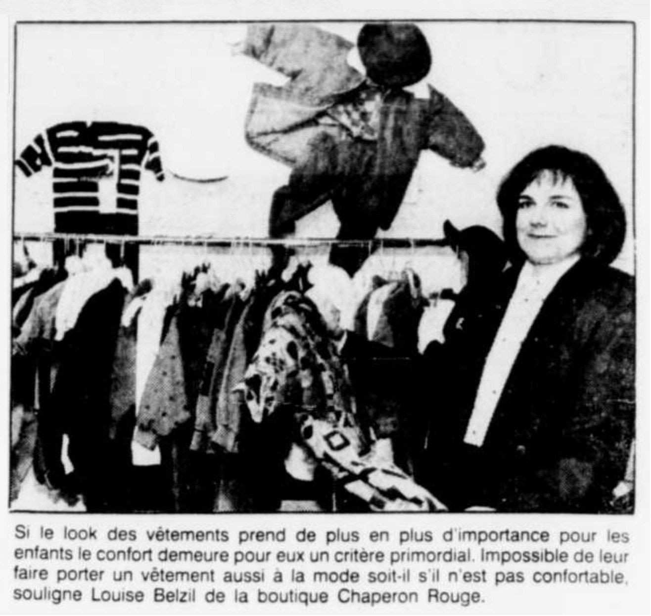 Louise Belzile de la boutique Le Petit Chaperon Rouge, devant un rayon de vêtements